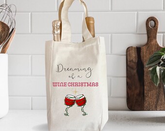 May include: A white canvas wine tote bag with a red and green design of two wine glasses with Christmas lights. The text on the bag reads "Dreaming of a Wine Christmas".