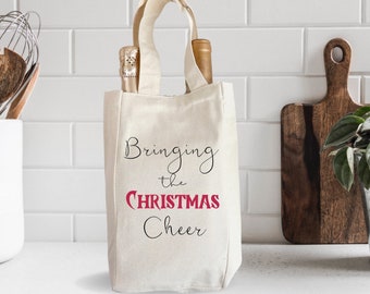 May include: A white canvas tote bag with black handles and the text "Bringing the Christmas Cheer" in black and red lettering. The bag is sitting on a white countertop.