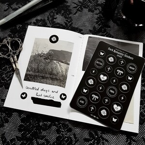 May include: A black and white sticker sheet with 24 stickers featuring various designs, including roses, hearts, butterflies, crosses, and text. The text on the stickers includes "rotten", "dream", "frail", "love", and "+". The sticker sheet is labeled "Dark Romantic Stickers 24 PCS".