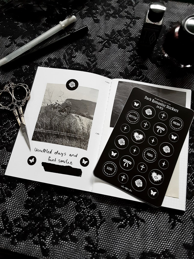 May include: A black and white sticker sheet with 24 stickers featuring various designs, including roses, hearts, butterflies, crosses, and text. The text on the stickers includes "rotten", "dream", "frail", "love", and "+". The sticker sheet is labeled "Dark Romantic Stickers 24 PCS".
