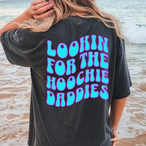 May include: A black t-shirt with a blue and purple graphic that says "Lookin for the Hoochie Daddies".
