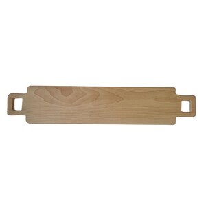 Peut inclure: Une planche à découper rectangulaire en bois, longue, avec deux poignées aux extrémités. La planche est en bois clair avec un grain naturel.