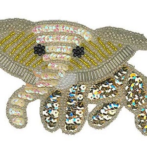 May include: A beaded elephant applique with gold and iridescent sequins. The elephant has black eyes and a light gray body.