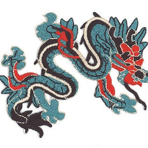 May include: Embroidered patch featuring a stylized dragon design. The dragon is primarily teal with black, red, and white accents. The patch is likely for clothing or accessories.
