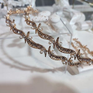 May include: Two gold-toned headbands with a delicate design of swirling lines and small white pearls.
