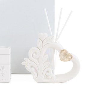Puede incluir: Difusor de cerámica blanca en forma de corazón con un acento de corazón dorado y detalles florales decorativos. El difusor viene con un juego de cañas para fragancia.