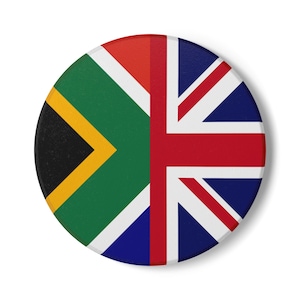 Puede incluir: Un pin circular con un diseño dividido que combina la bandera de Sudáfrica a la izquierda con sus colores verde, negro, amarillo, blanco y rojo, y la bandera británica Union Jack a la derecha con su patrón de cruz en azul, blanco y rojo.