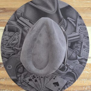 May include: A grey felt hat with a teardrop crown and a thin leather tassel on the side. The brim features a detailed black and grey graphic print of playing cards, revolvers, a whiskey glass, and a bottle labelled Jameson Irish Whiskey.