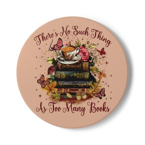 Op de afbeelding: Een ronde onderzetter met een licht perzikkleurige achtergrond met een stapel van vier vintage boeken met daarop een theekopje en schoteltje. Het ontwerp bevat kleurrijke vlinders, herfstbladeren, rozen en eikels met de tekst There's No Such Thing As Too Many Books.