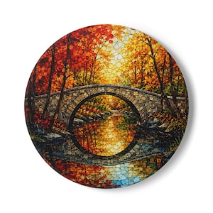 Könnte beinhalten: Ein rundes Wandbild mit einer Mosaik-Landschaft, die eine Steinbrücke über einem ruhigen Bach zeigt. Die Szene ist gefüllt mit herbstlichem Laub in Rot-, Orange- und Gelbtönen, wobei sich die Brücke im Wasser darunter spiegelt.
