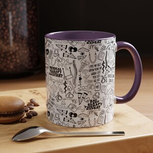 May include: A white ceramic coffee mug with a purple rim and handle. The mug features a black and white pattern of physical therapy related icons and text, including "Physical Therapy Assistant", "Eat Sleep Therapy Repeat", and "I put my belt upon your hip when I lift you lift".