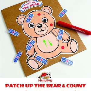 Puede incluir: Un juego imprimible titulado Patch Up The Bear que muestra un oso de dibujos animados sobre un tablero marrón. El oso tiene manchas rojas y pegatinas de tiritas azules numeradas del 1 al 10. Incluye un rotulador rojo borrable.