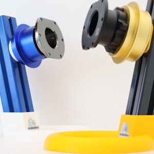 Op de afbeelding: Twee verschillende camerabevestigingen, een met een blauwe basis en een met een gele basis. Beide bevestigingen hebben een zwarte metalen camera-adapter. De bevestigingen zijn gemaakt van aluminium en hebben een logo op de basis.