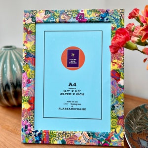 May include: A rectangular picture frame with a vibrant, multi-coloured floral and geometric pattern. The light blue insert displays the text: Flare and Frame, A4 Approx. 11.7" x 8.3" 29.7cm x 21cm, Find us on Etsy Instagram @flareandframe.