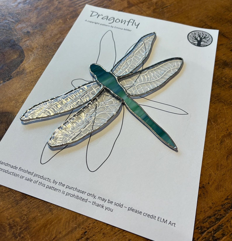 Finished Dragonfly Stained glass artwork placed on top of the pattern used to create it. The pattern is for sale in this listing.