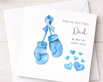 May include: A square greeting card featuring a watercolor illustration of two light blue boxing gloves tied together with a light blue awareness ribbon. The text reads YOU'VE GOT THIS Dad & WE'VE GOT YOU, accompanied by several small blue hearts.