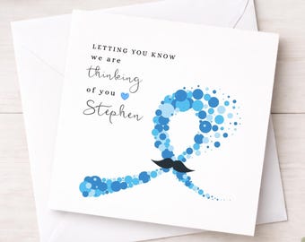 May include: A square white greeting card with a blue awareness ribbon made of various sized circles. The card features the text "LETTING YOU KNOW we are thinking of you Stephen" and a small blue heart, with a black mustache icon on the ribbon.