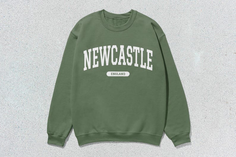K&ouml;nnte beinhalten: Ein gr&uuml;ner Pullover mit wei&szlig;em Text, der "NEWCASTLE ENGLAND" lautet.