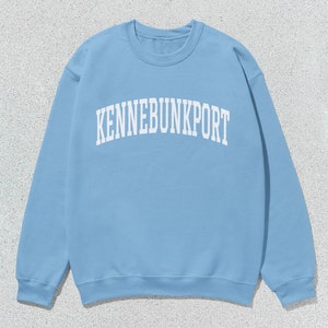 May include: A light blue sweatshirt with the text "KENNEBUNKPORT" printed in white.