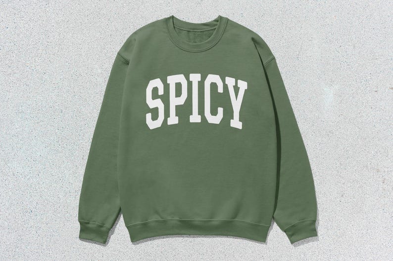 Może przedstawiać: Zielony sweter z nadrukiem "SPICY" w kolorze białym z przodu.