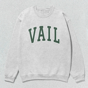 May include: A gray sweatshirt with the word "VAIL" printed in green on the front.