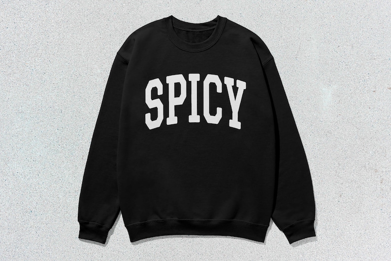 Może przedstawiać: Czarna bluza z białym napisem "SPICY" w stylu uniwersyteckim.
