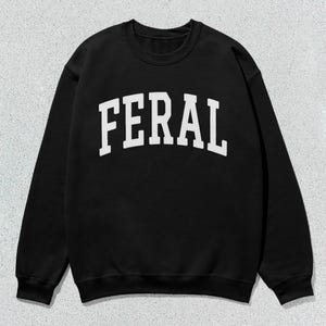 May include: Black sweatshirt with a white "FERAL" graphic printed on the front.