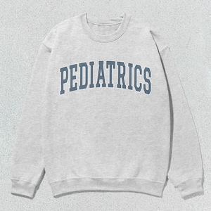 Puede incluir: Una sudadera gris con la palabra "PEDIATRICS" impresa en azul en la parte delantera.