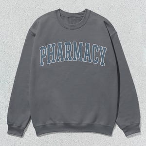 May include: A gray sweatshirt with the word "PHARMACY" printed in a blue and white arch across the front.