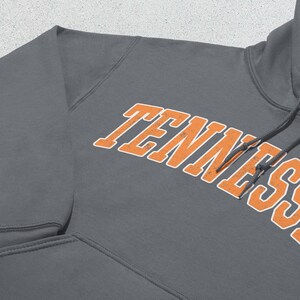 May include: A charcoal gray hooded sweatshirt with the word "TENNESSEE" in orange lettering with white outlines.