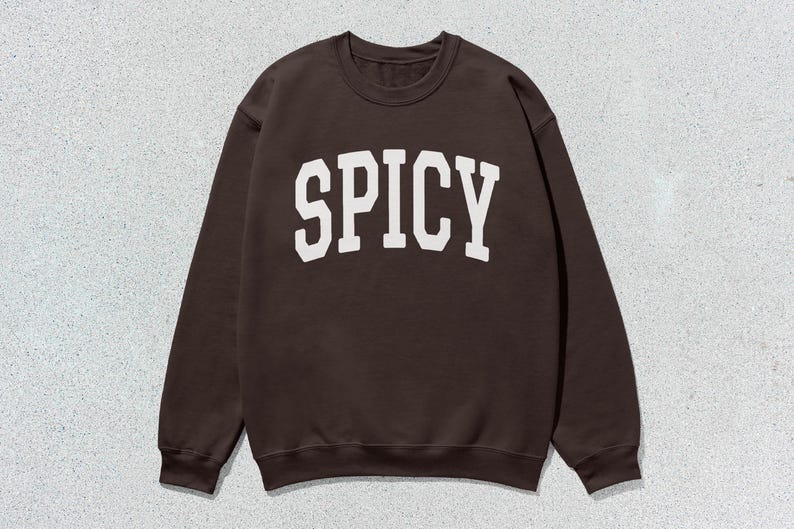 Może przedstawiać: Brązowa bluza z nadrukiem "SPICY" w kolorze białym na przodzie.