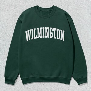 May include: A dark green sweatshirt with the word "WILMINGTON" printed in white on the front.