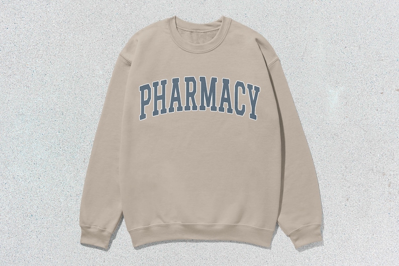 May include: A tan sweatshirt with the word "PHARMACY" printed in blue on the front.