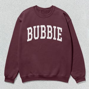May include: Burgundy sweatshirt with white text that reads "BUBBIE" in an arch.