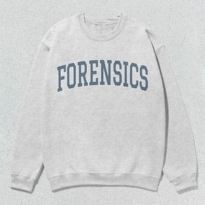Könnte beinhalten: Ein grauer Pullover mit dem Wort "FORENSICS" in Blau auf der Vorderseite.