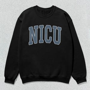 Puede incluir: Sudadera negra de cuello redondo con la palabra "NICU" en letras grandes y en bloque en el pecho. Las letras son de un azul apagado con un contorno blanco. La sudadera tiene mangas largas y un dise&ntilde;o cl&aacute;sico e informal.