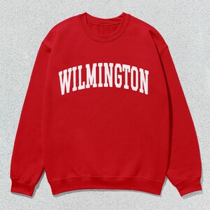 May include: Red sweatshirt with white text that reads "WILMINGTON" in a collegiate font.