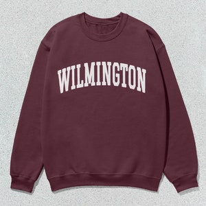 May include: A maroon sweatshirt with the word "WILMINGTON" printed in white on the front.