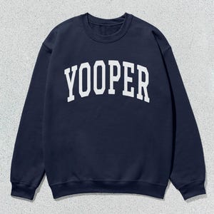 Peut inclure: Un sweat-shirt bleu marine avec le mot "Yooper" imprimé en blanc sur le devant.