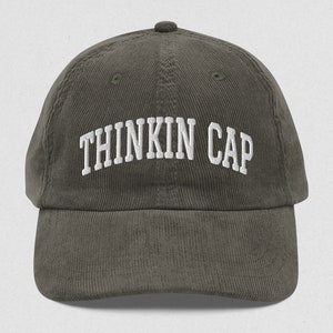 May include: A dark green corduroy baseball cap with white embroidered text that reads "Thinkin Cap".