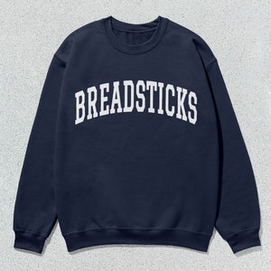 May include: A navy blue sweatshirt with the word "BREADSTICKS" printed in white in an arched font.