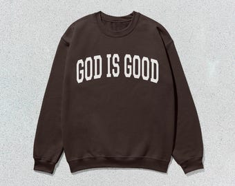 May include: A brown sweatshirt with the text "GOD IS GOOD" printed in white on the front.