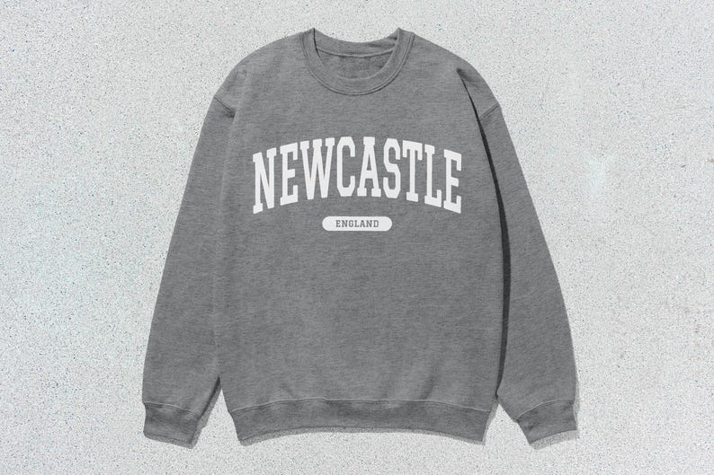 K&ouml;nnte beinhalten: Grauer Sweatshirt mit wei&szlig;em Text, der "NEWCASTLE ENGLAND" lautet.