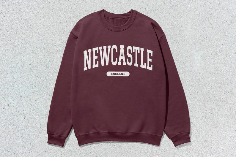 K&ouml;nnte beinhalten: Ein weinroter Pullover mit wei&szlig;em Text, der "NEWCASTLE ENGLAND" lautet.