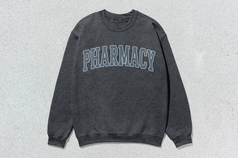 May include: A dark gray sweatshirt with the word "PHARMACY" printed in a light blue and gray arch across the front.