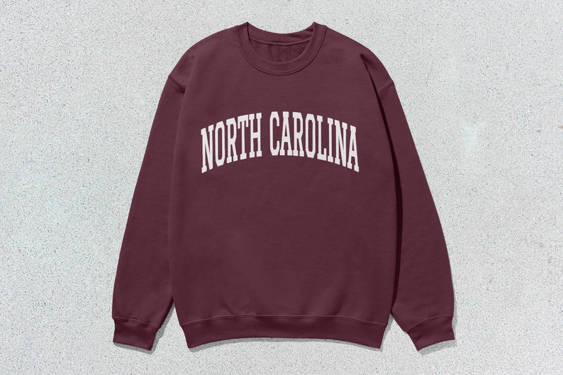 Pu&ograve; includere: Una felpa color bordeaux con la scritta "NORTH CAROLINA" stampata in bianco sul davanti.