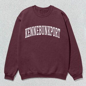 May include: A maroon sweatshirt with the text "KENNEBUNKPORT" printed in white on the front.