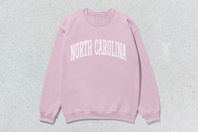 Pu&ograve; includere: Una felpa rosa con la scritta "NORTH CAROLINA" in bianco.