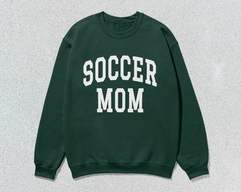 Puede incluir: Una sudadera verde oscuro con el texto "SOCCER MOM" en blanco.