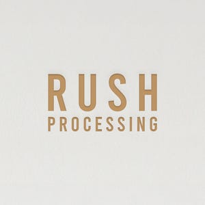 Può includere: Sfondo bianco con le parole "RUSH PROCESSING" in un carattere dorato senza grazie. Il testo è centrato e sembra leggermente in rilievo sulla superficie.